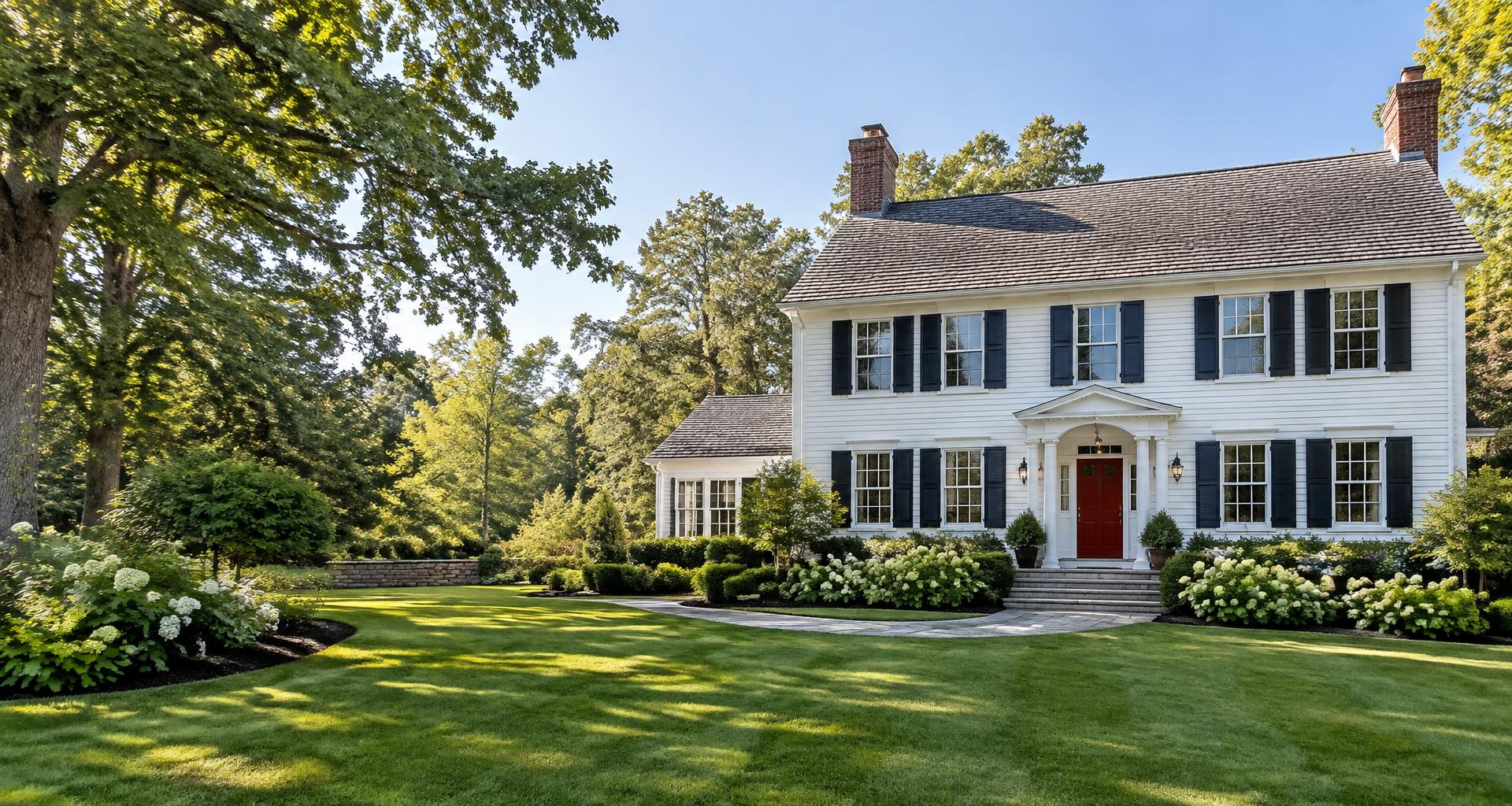 Illustrative freshly painted New England colonial home with white siding and navy shutters